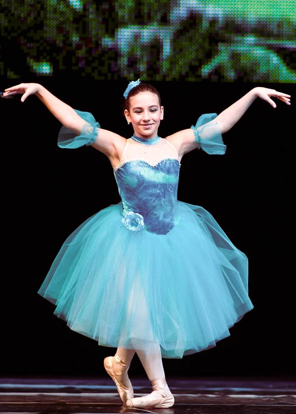 A Nika dancer on stage in a teal tutu